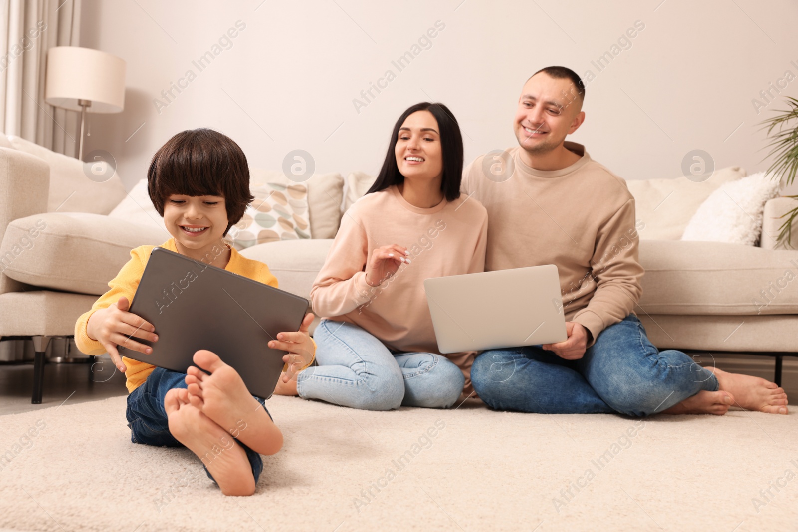 Photo of Happy family with gadgets on floor at home