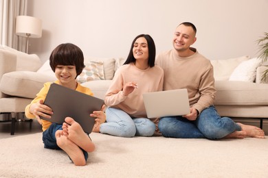 Happy family with gadgets on floor at home