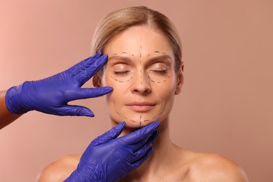 Photo of Doctor checking patient's face before cosmetic surgery operation on light brown background