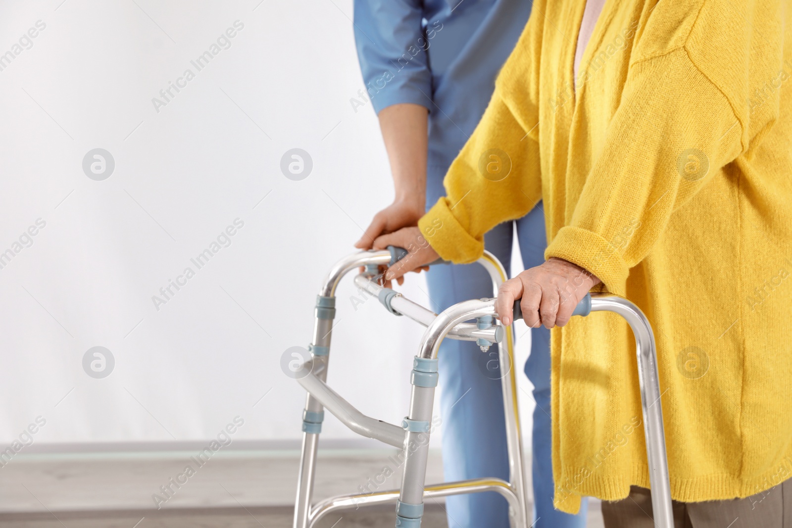 Photo of Nurse assisting senior woman with walker in hospital, closeup. Space for text