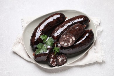 Tasty blood sausages with parsley served on light grey table, top view