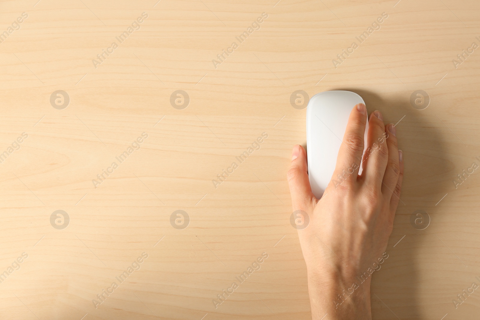 Photo of Woman using computer mouse on wooden background, top view. Space for text