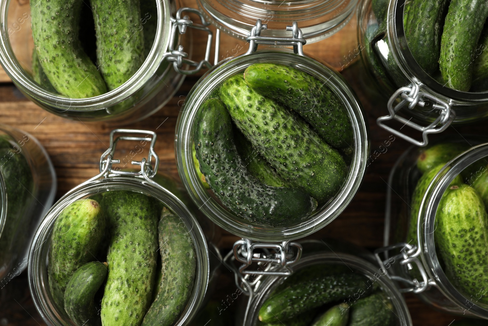 Photo of Pickling jars with fresh cucumbers on wooden table, flat lay