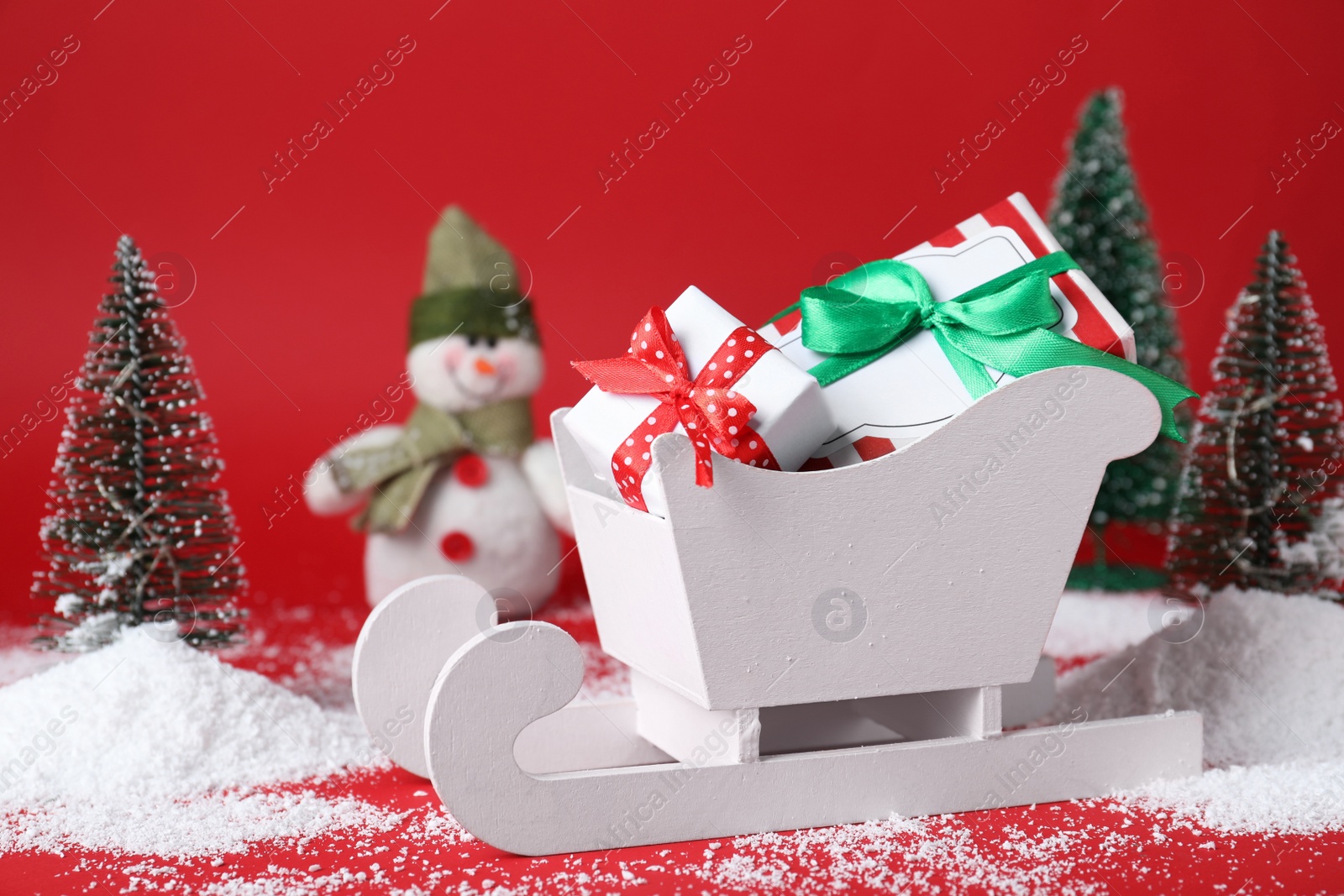 Photo of Sleigh with gift boxes and Christmas decorations on red background