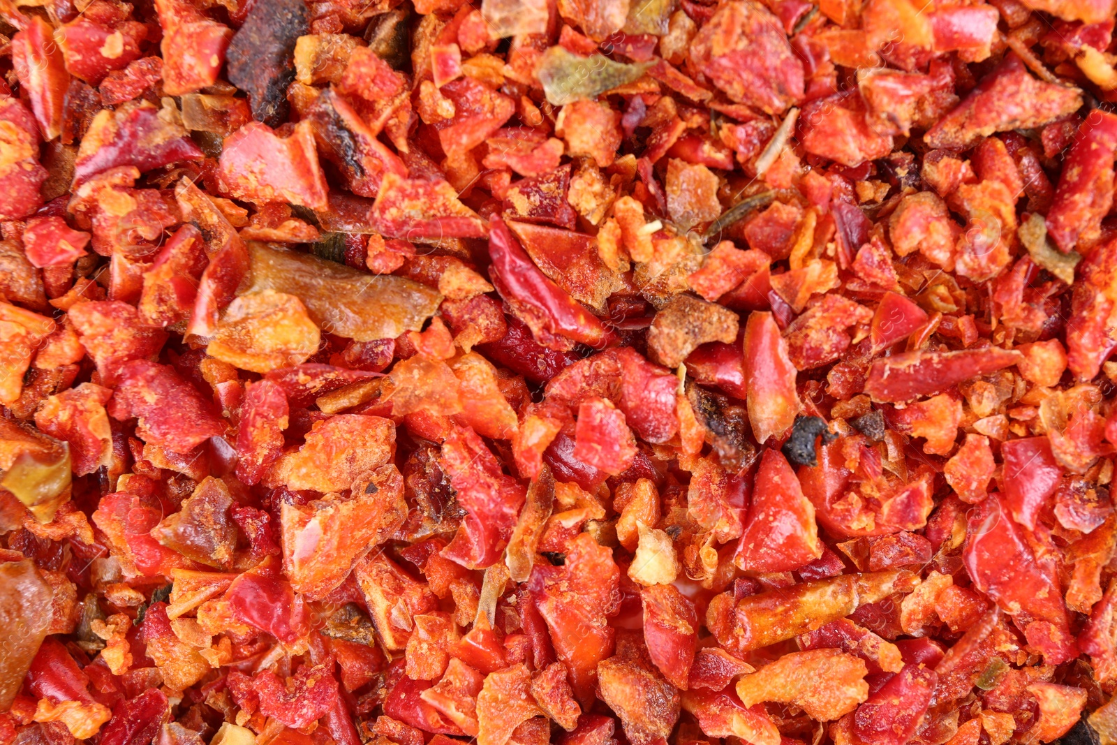 Photo of Aromatic spice. Red chili pepper flakes as background, top view