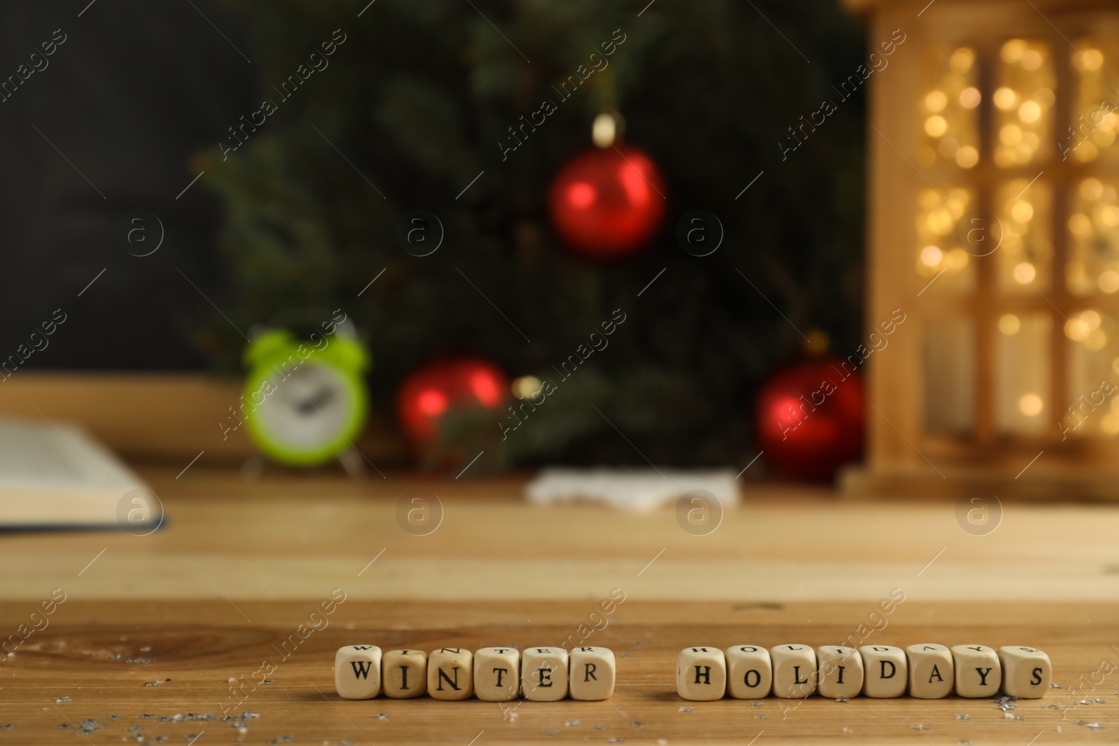 Photo of Wooden cubes with phrase Winter Holidays and blurred Christmas decor on background. Space for text