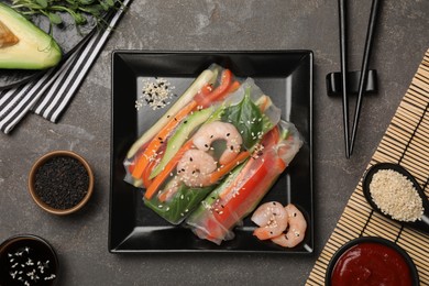 Photo of Delicious rolls wrapped in rice paper served on grey table, flat lay