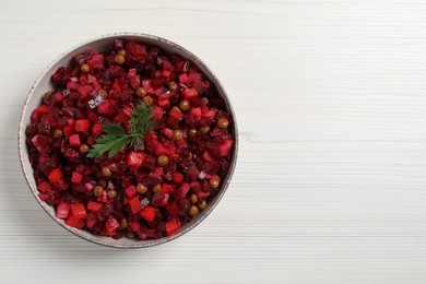 Bowl of delicious fresh vinaigrette salad on white wooden table, top view. Space for text