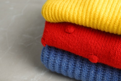 Photo of Stack of folded knitted sweaters on table, closeup. Space for text