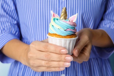 Woman holding cute sweet unicorn cupcake, closeup