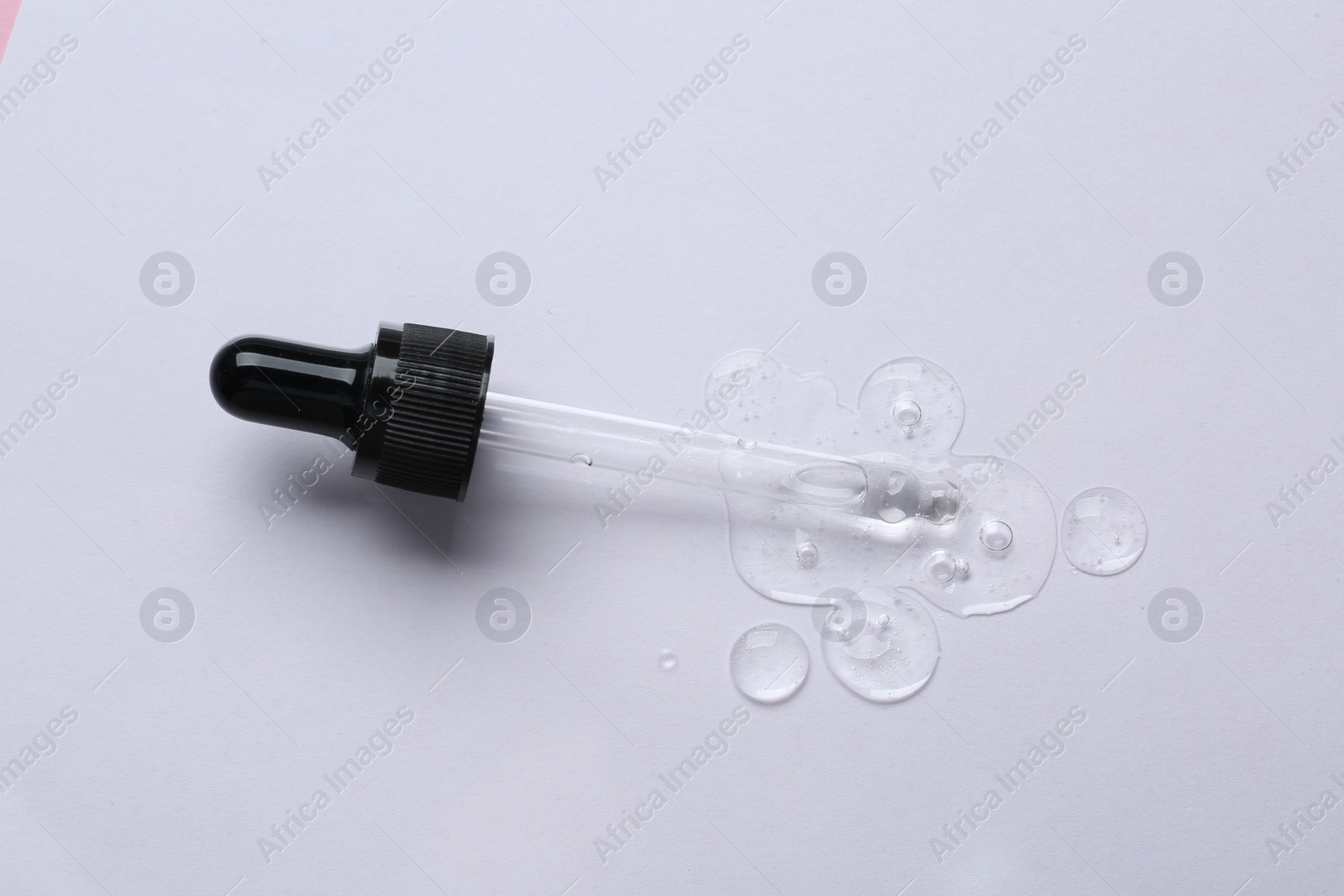 Photo of Pipette with cosmetic serum on white background, top view
