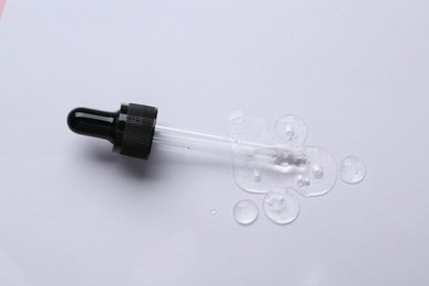 Pipette with cosmetic serum on white background, top view