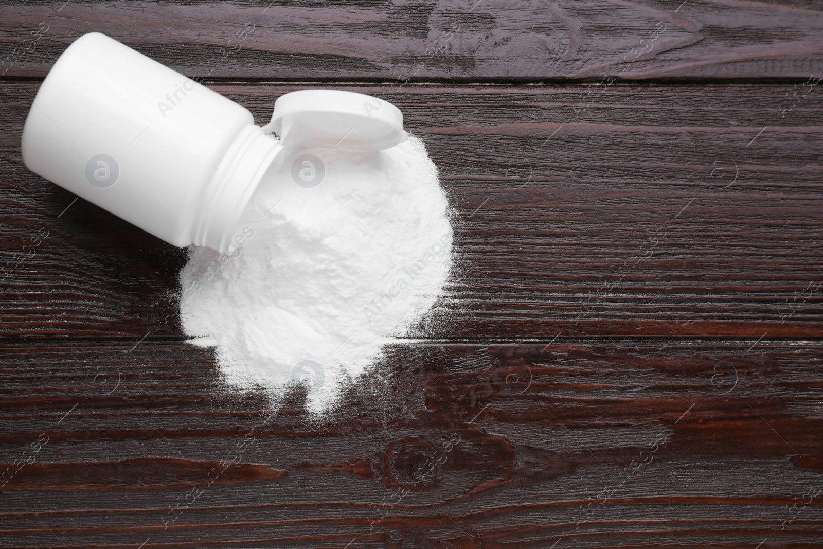 Photo of Jar of sweet powdered fructose on black wooden table, top view. Space for text