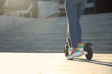 Woman riding electric kick scooter outdoors, closeup. Space for text