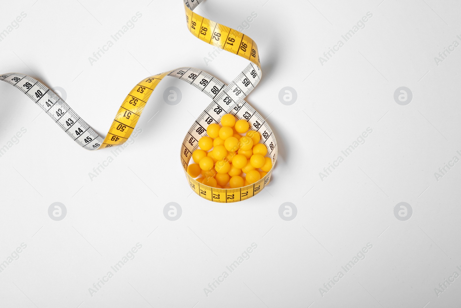 Photo of Weight loss pills and measuring tape on white background