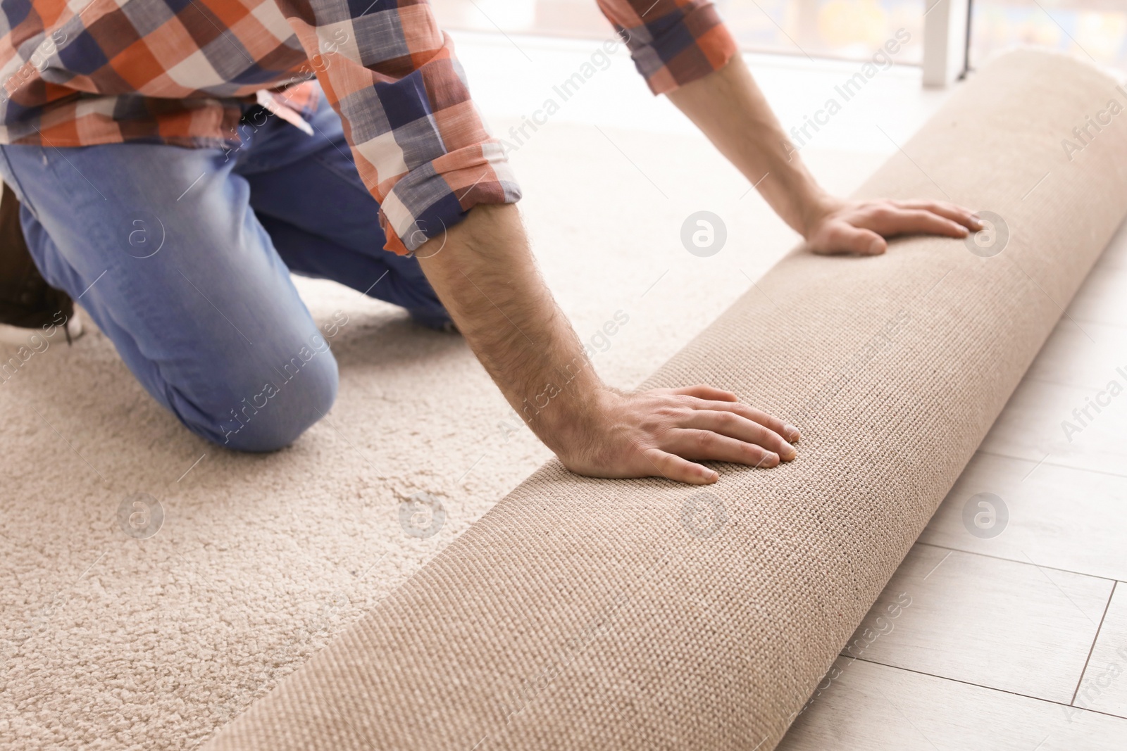 Photo of Man rolling out new carpet flooring in room