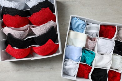 Organizers with folded women's underwear on light wooden table, flat lay