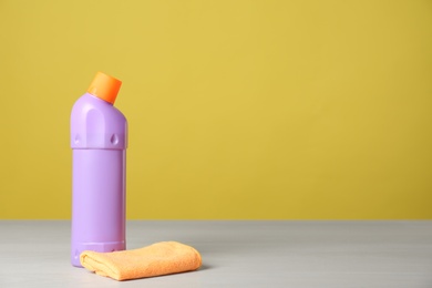 Photo of Bottle of cleaning product and microfiber cloth on light table. Space for text