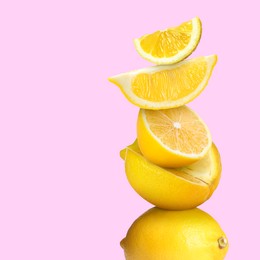 Stacked cut and whole lemons on pale pink background, space for text