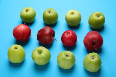 Photo of Ripe red and green apples on light blue background