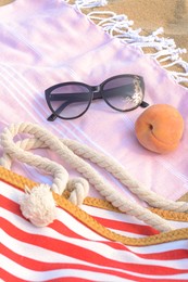 Beautiful sunglasses, bag and peach on blanket