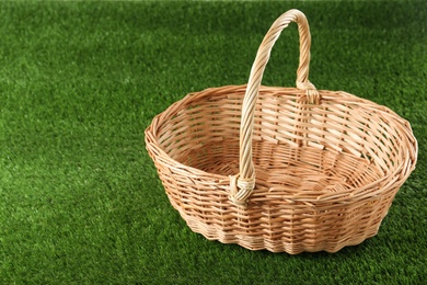 Photo of Empty wicker basket on green lawn, space for text. Easter item