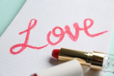 Photo of Notebook with word Love and red lipstick on turquoise background, closeup