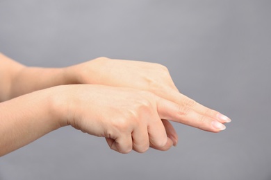 Woman showing word same on grey background, closeup. Sign language