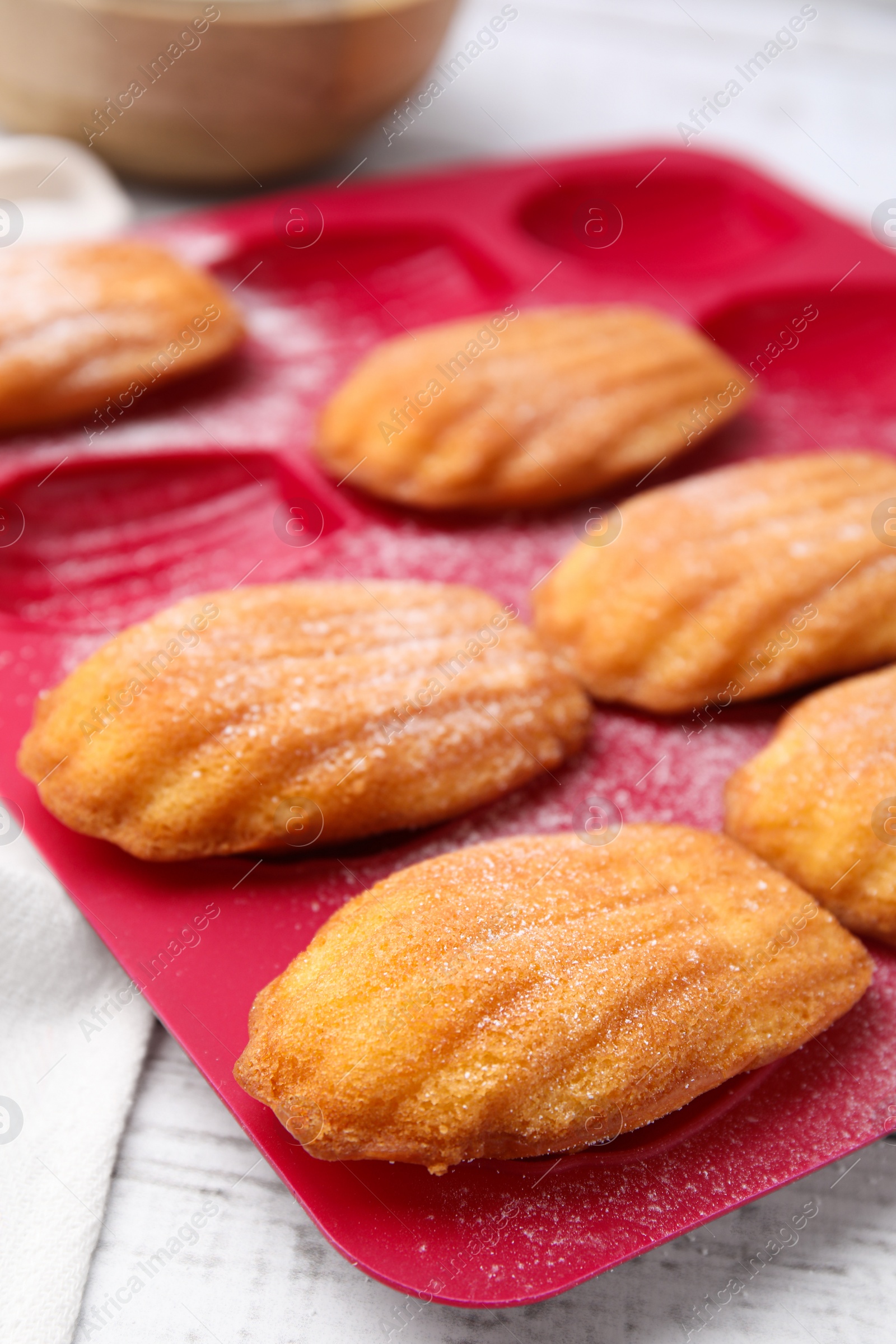 Photo of Delicious madeleine cookies in baking mold on white wooden table, closeup