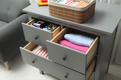 Chest of drawers with different folded clothes indoors