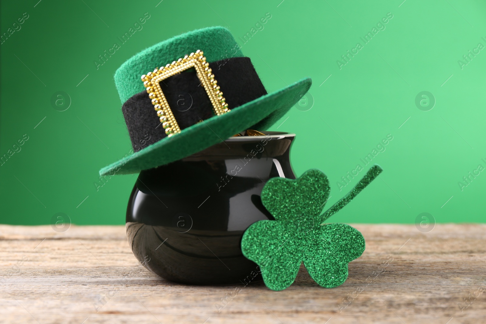 Photo of St. Patrick's day. Pot of gold with leprechaun hat and decorative clover leaf on wooden table