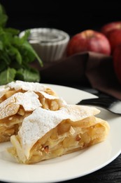 Photo of Delicious apple strudel with almonds and powdered sugar on plate, closeup. Space for text