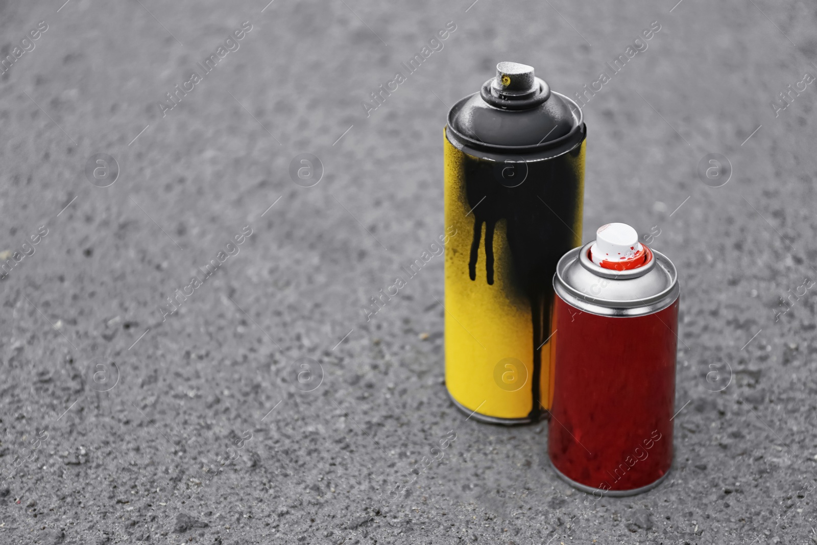 Photo of Used cans of spray paint on asphalt. Space for text