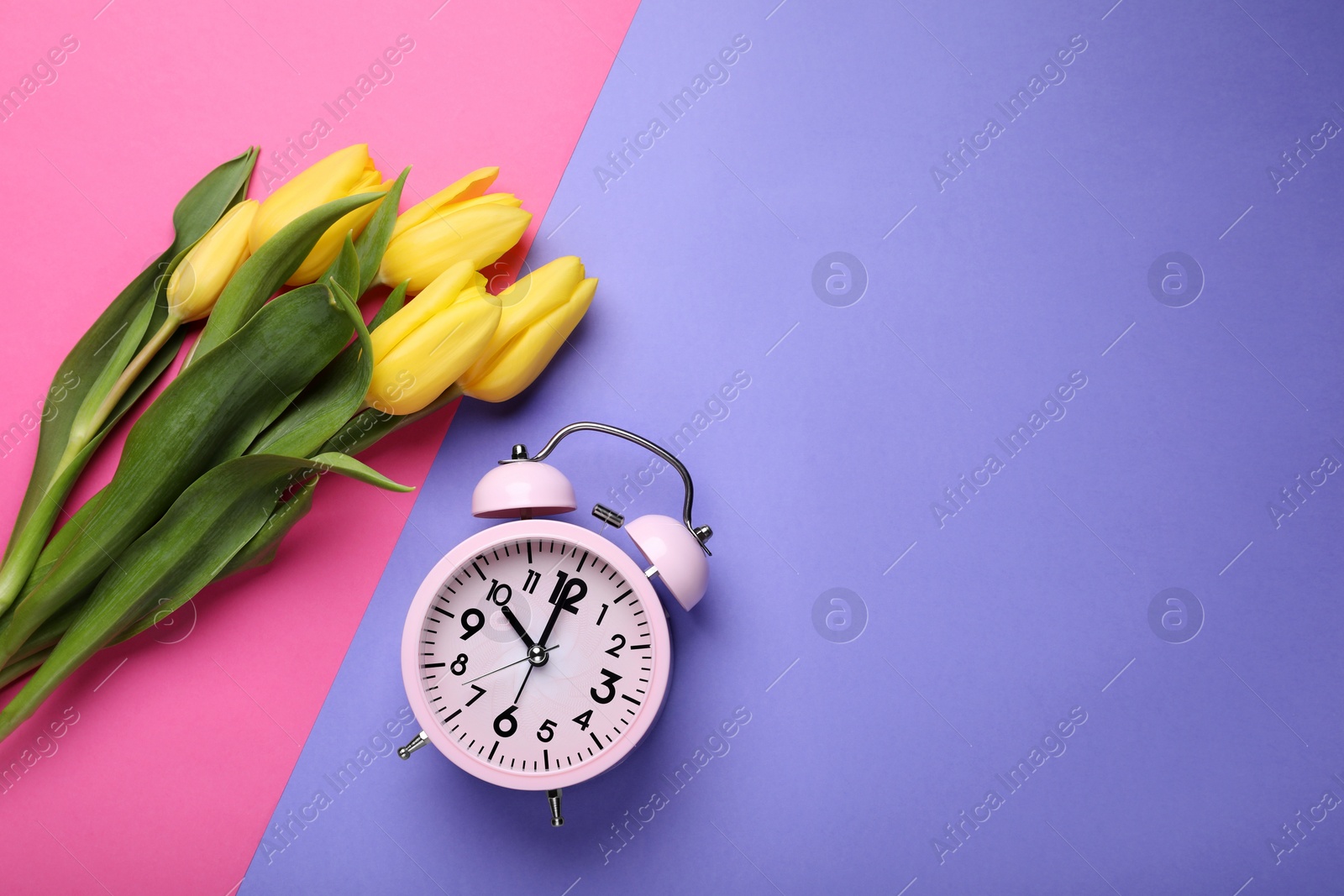 Photo of Pink alarm clock and beautiful tulips on color background, flat lay with space for text. Spring time