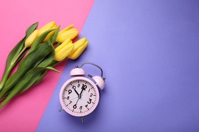 Pink alarm clock and beautiful tulips on color background, flat lay with space for text. Spring time