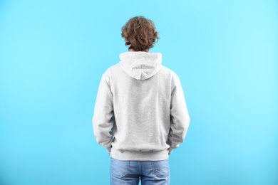 Man in hoodie sweater on color background. Space for design