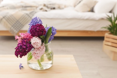 Beautiful hyacinths in glass vase on table indoors, space for text. Spring flowers