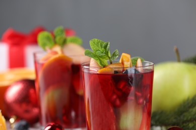 Photo of Aromatic Sangria drink in glasses, ingredients and Christmas decor on table, closeup