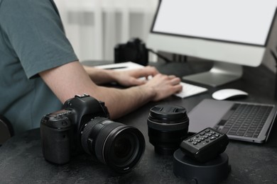 Photo of Camera on dark table, closeup. Photographer working with computer indoors, selective focus