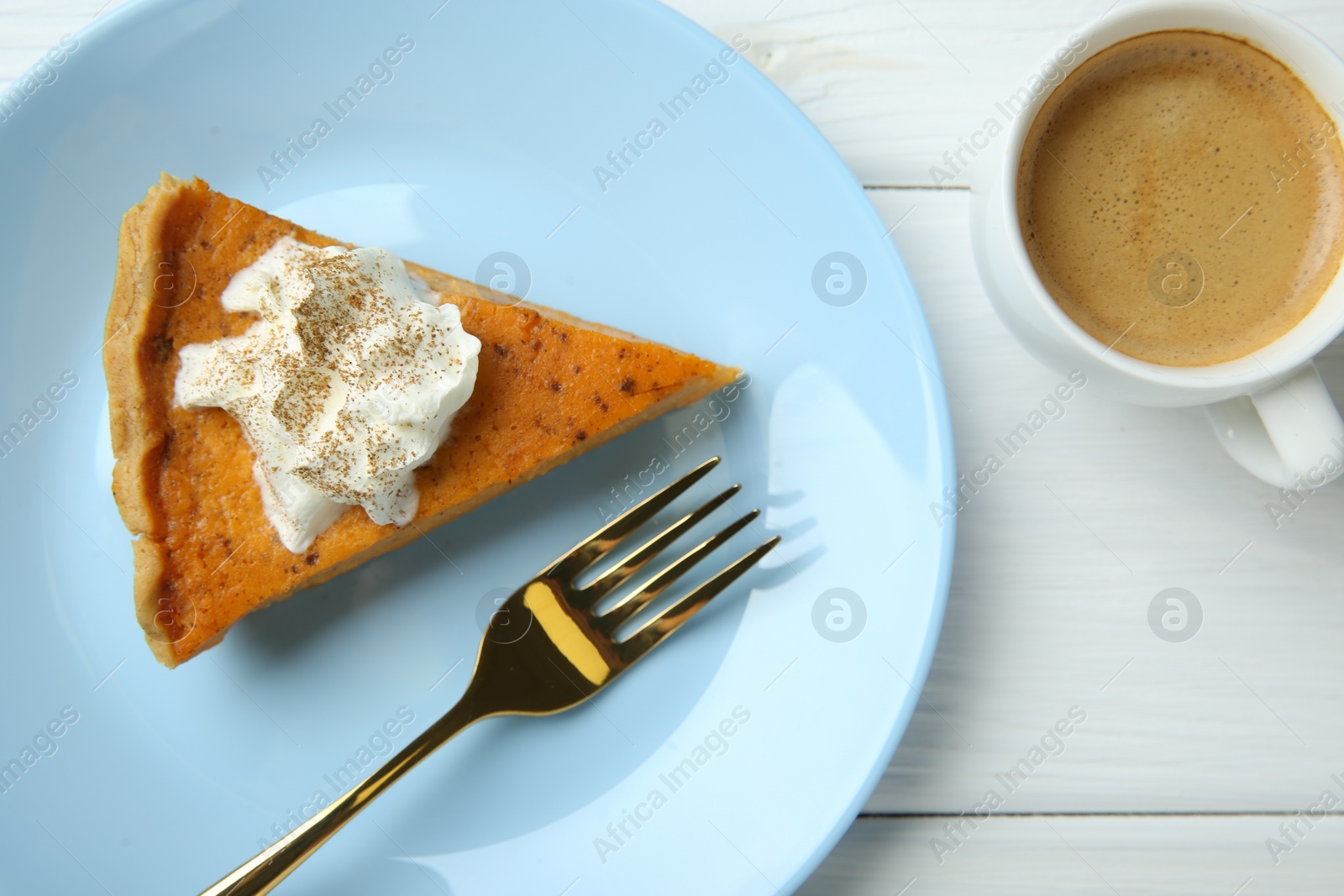 Photo of Delicious pumpkin pie with whipped cream, fork and cup of coffee on white wooden table, flat lay