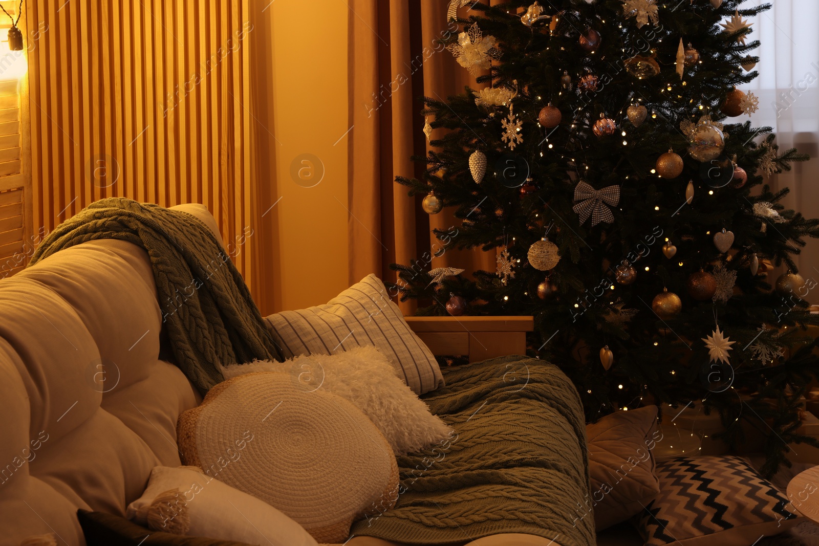 Photo of Comfortable sofa near Christmas tree in room