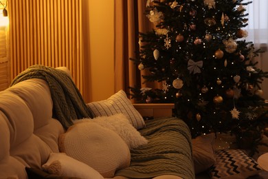 Comfortable sofa near Christmas tree in room