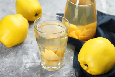 Photo of Delicious quince drink and fresh fruits on grey table, closeup