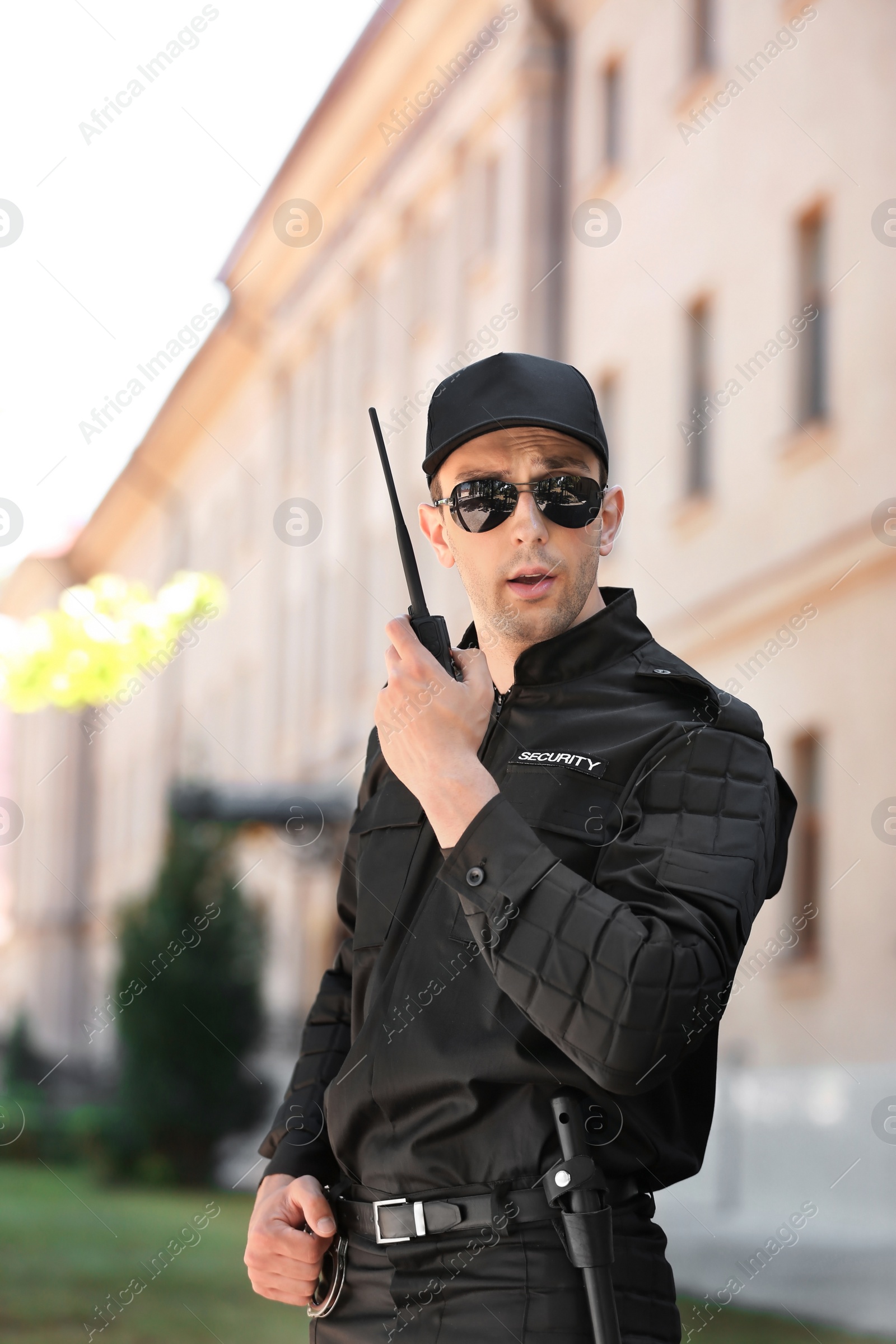 Photo of Male security guard using portable radio transmitter outdoors