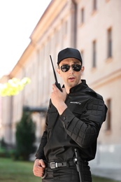 Male security guard using portable radio transmitter outdoors