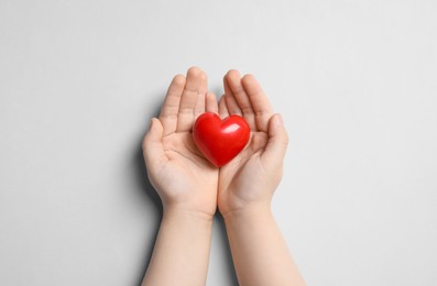 Photo of Child holding red heart on light grey background, top view