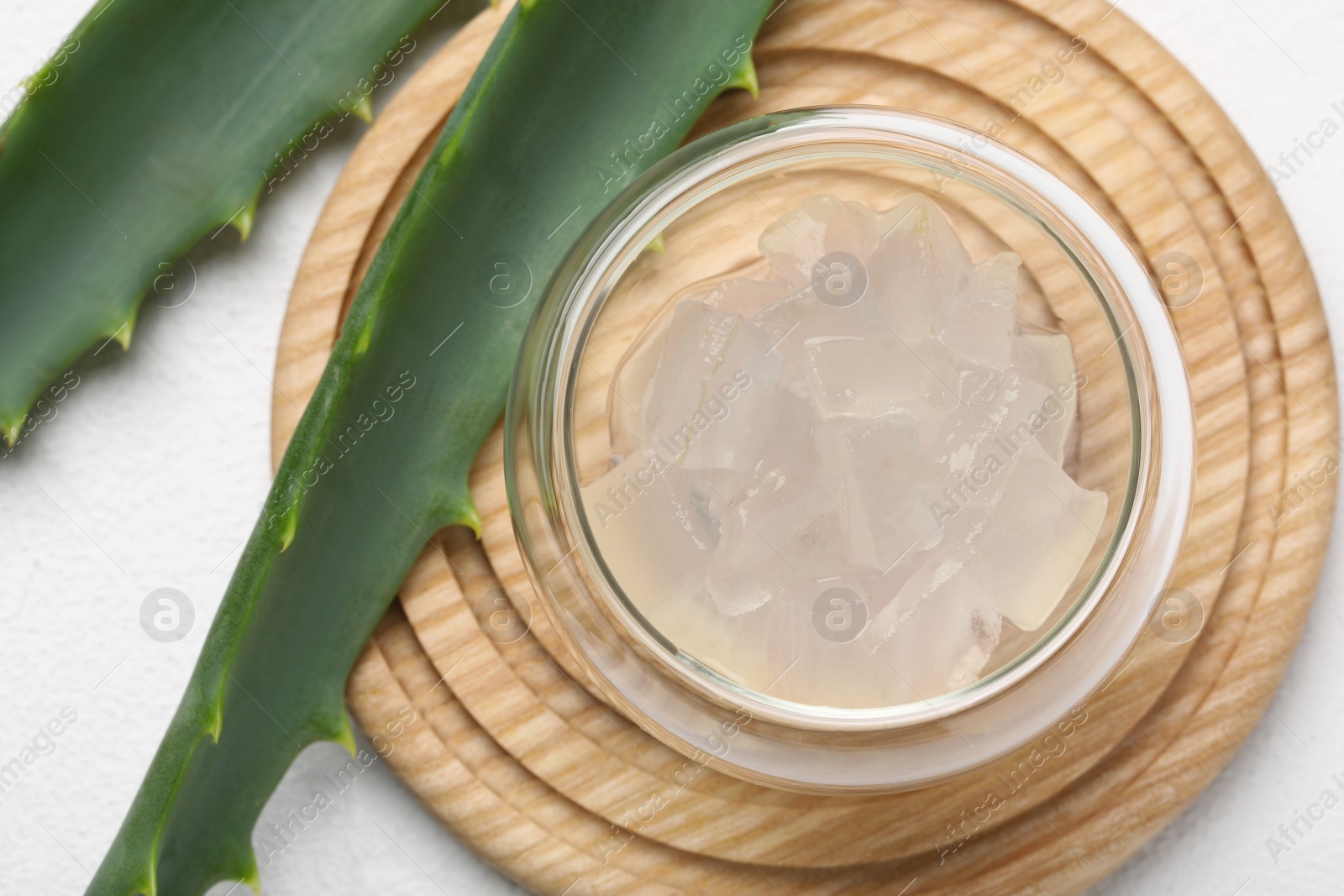 Photo of Aloe vera gel and slices of plant on white background, flat lay