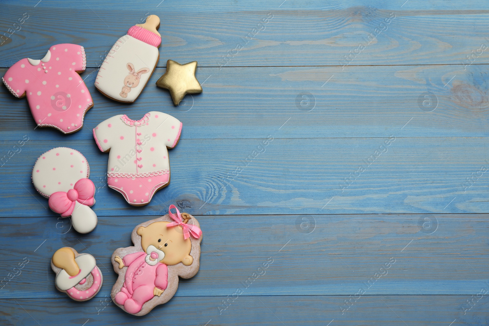 Photo of Cute tasty cookies of different shapes and space for text on light blue wooden table, flat lay. Baby shower party