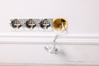 Photo of Broken power sockets on white wall indoors