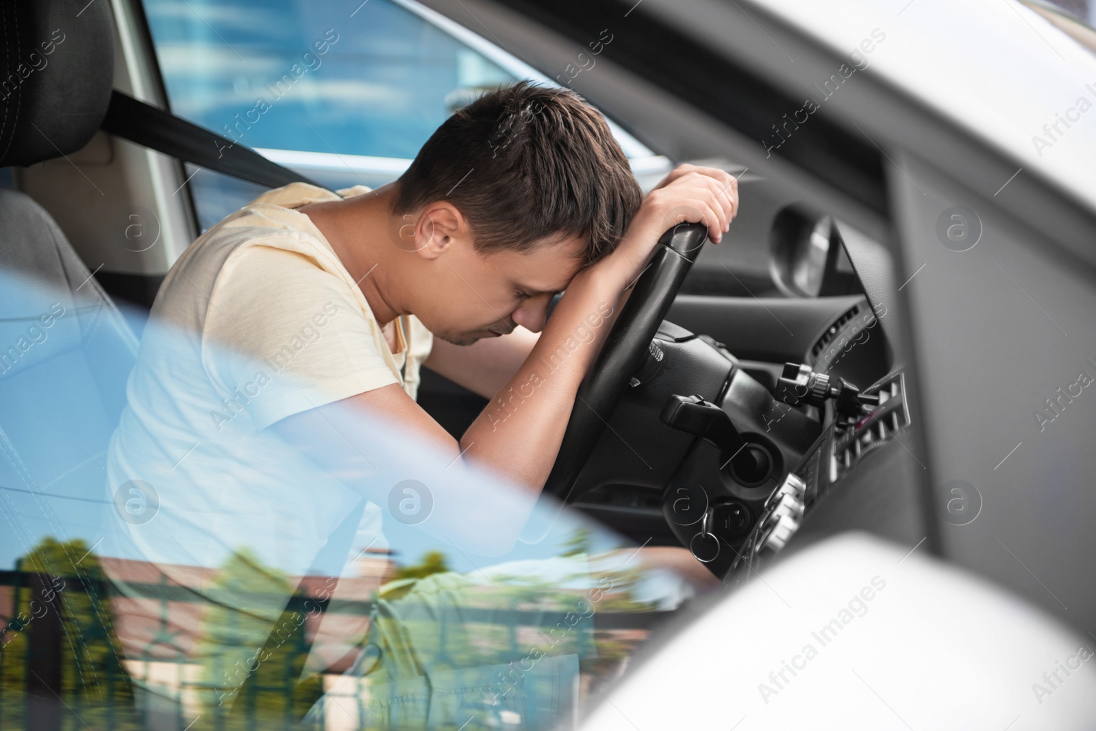 Photo of Tired man sleeping on steering wheel in his car